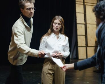 Kolme näyttelijää harjoittelee kohtausta ja käsikirjoitusta teatteritilassa